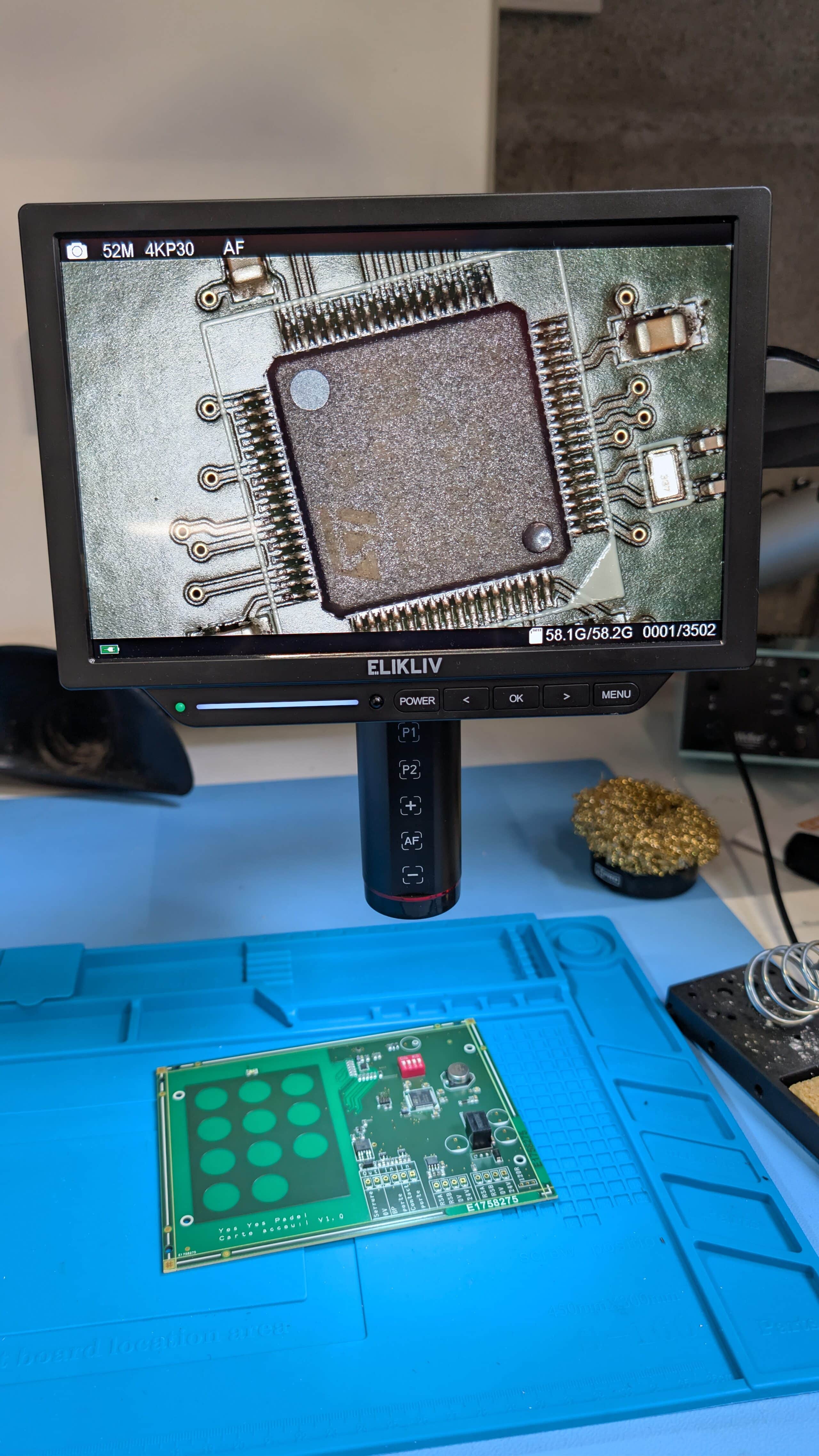 Microscope électronique visualisant un prototype de carte électronique avec un circuit intégré complexe.
