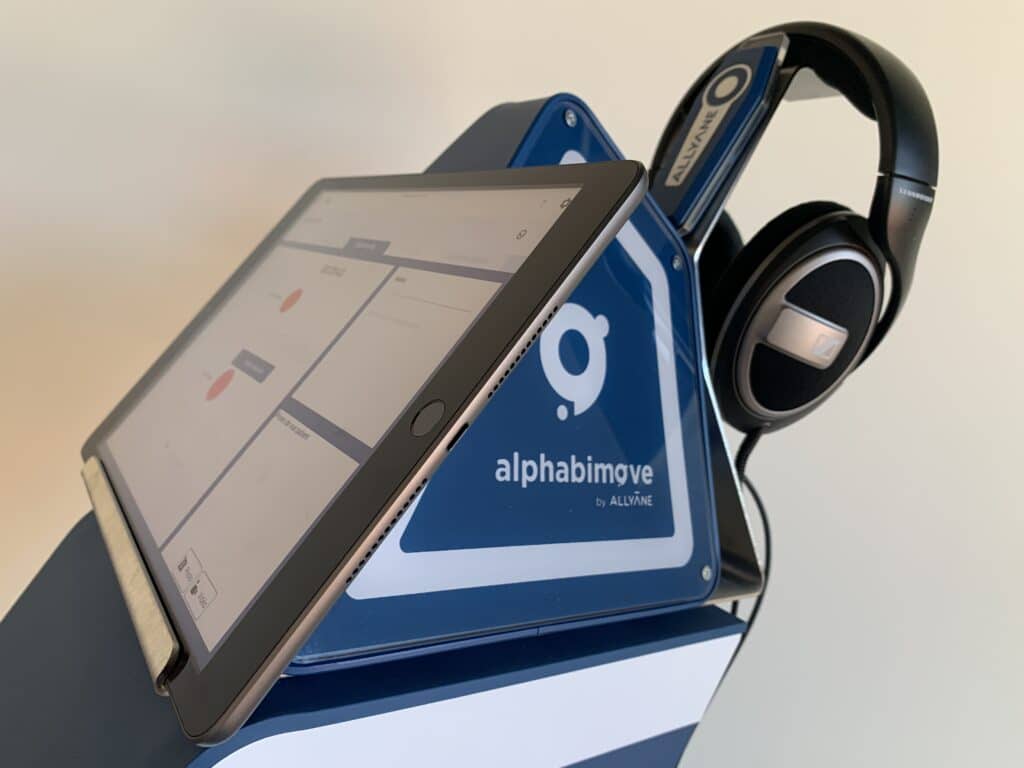 Tablette Alphabimove avec casque audio. L'écran affiche l'interface Alphabimove.