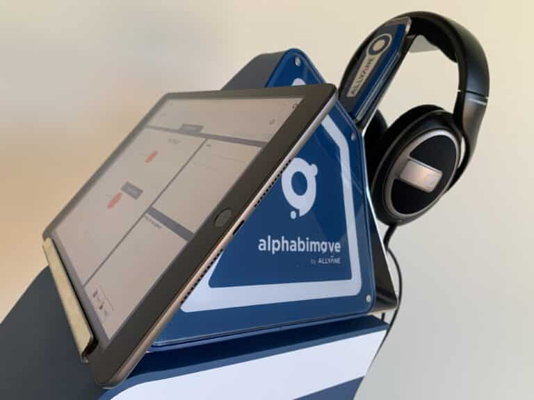 Tablette Alphabimove avec casque audio. L'écran affiche l'interface Alphabimove.
