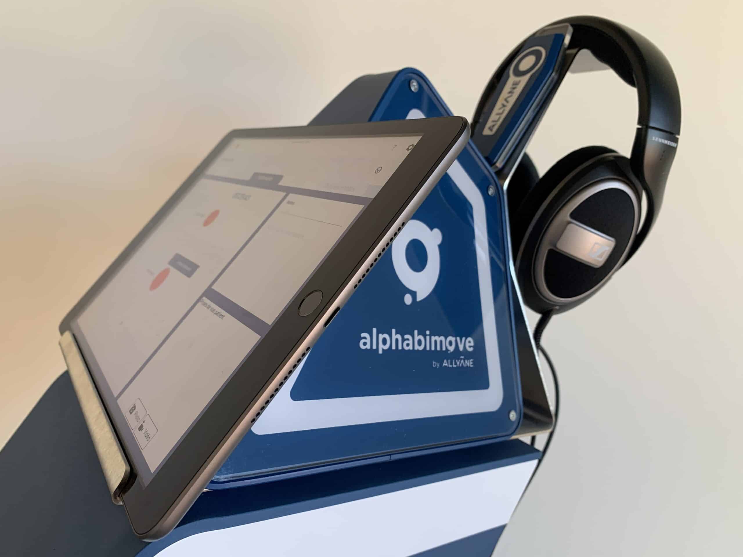 Tablette Alphabimove avec casque audio. L'écran affiche l'interface Alphabimove.