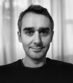 Portrait en noir et blanc d'un homme souriant, regardant la caméra.