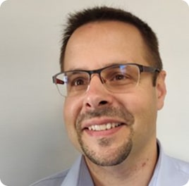 Portrait d'un homme souriant avec des lunettes.